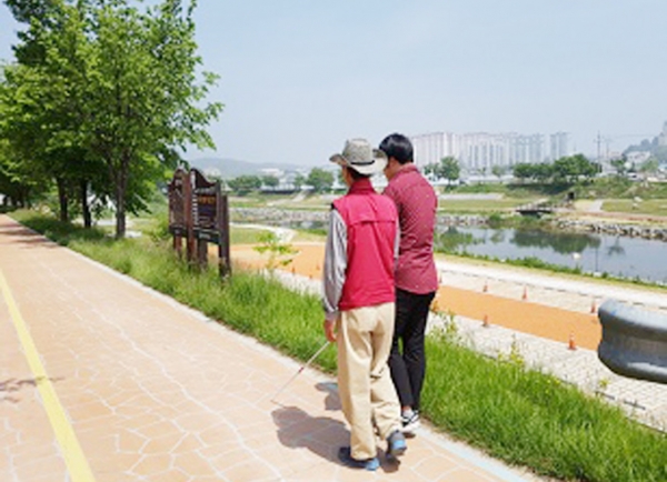 김운태 사회복무요원이 시각장애인 어르신의 산책을 도와주고 있다.